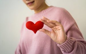 lady in pink sweater holding a red heart