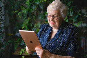 elderly lady sitting and holding tablet, smiling