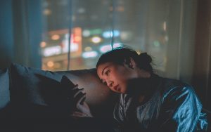 woman sitting in dark on couch looking at her phone