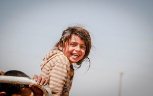 refugee child, outside, smiling