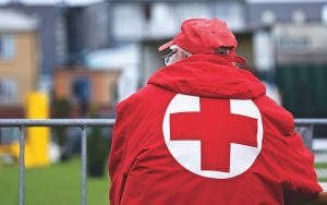 man standing with his back to the camera, wearing a red cross jacket