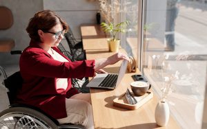 a lady in a wheelchair at a table with a laptop