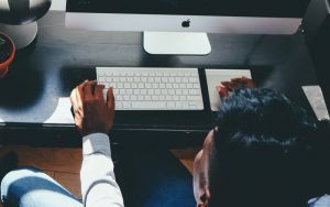 Man sitting at table in front of Mac computer