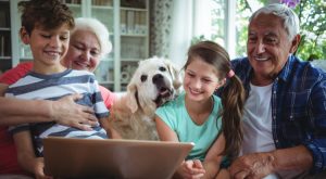 grandparents with grandkids and family dog holding tablet computer and smiling