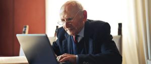 elderly man at table with laptop