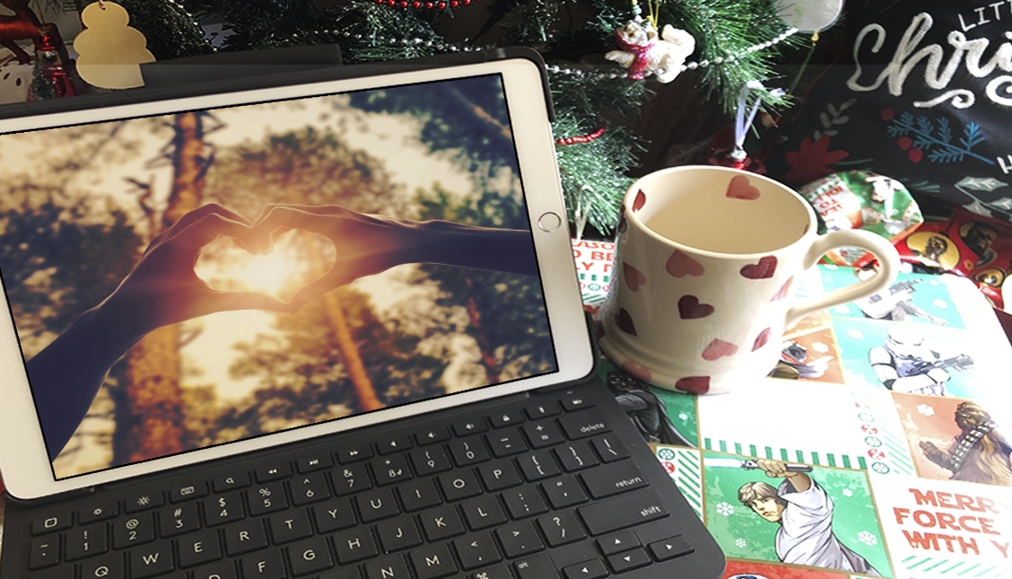 holiday scene with an ipad and a mag, hands in a heart on ipad screen