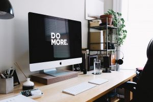 a desk with a desktop apple computer that has do more on screen