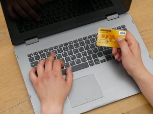 laptop with person holding credit card for online banking