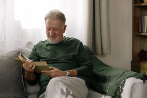 man sitting on couch with book, smiling