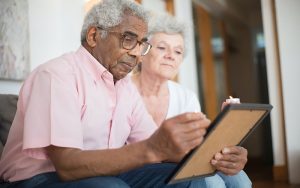 elderly man and woman sitting down with a device