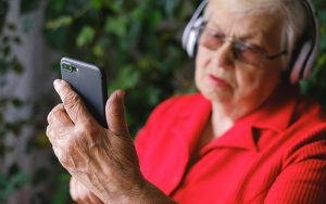 an elderly woman is holding a mobile phone in her raised hand