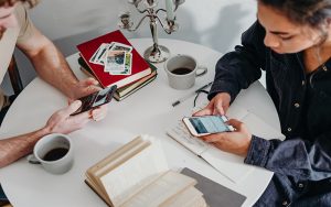 a man and a woman sitting at a table holding mobile phones