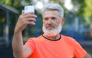 a man holding a mobile phone away from his face, staring at screen