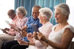 a group of people sitting in a row, holding a tablet device and smiling