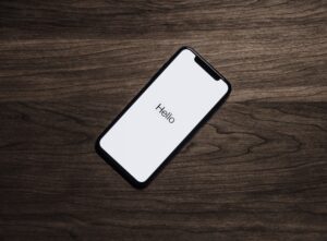 a mobile phone on a table, the phone has a white background with the word hello on it.