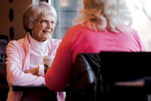 an elderly woman sits facing another woman, they are deep in conversation while sitting at a table