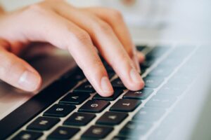 A hand on a laptop keyboard.